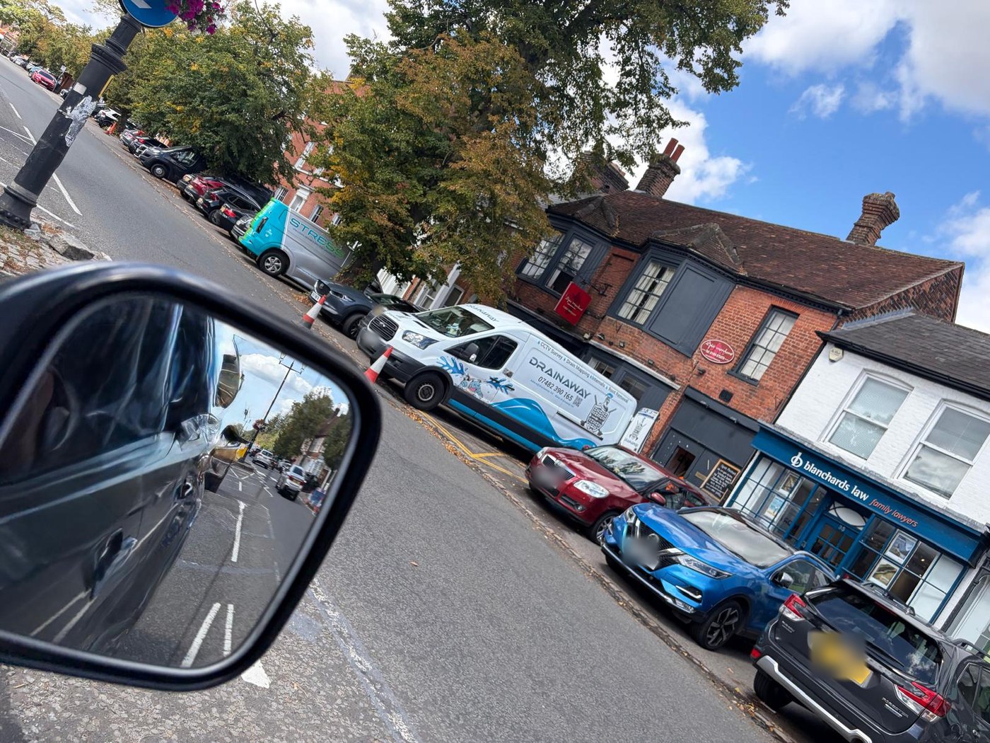 A DrainAway van parked and coned off on a Buckinghamshire high street, outside a row of shops and offices