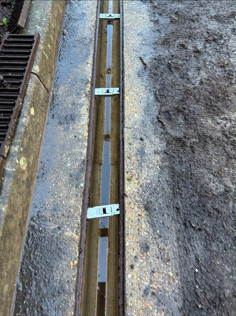 The same channel drain jetted clean and running clear, with the guards being refitted one by one.