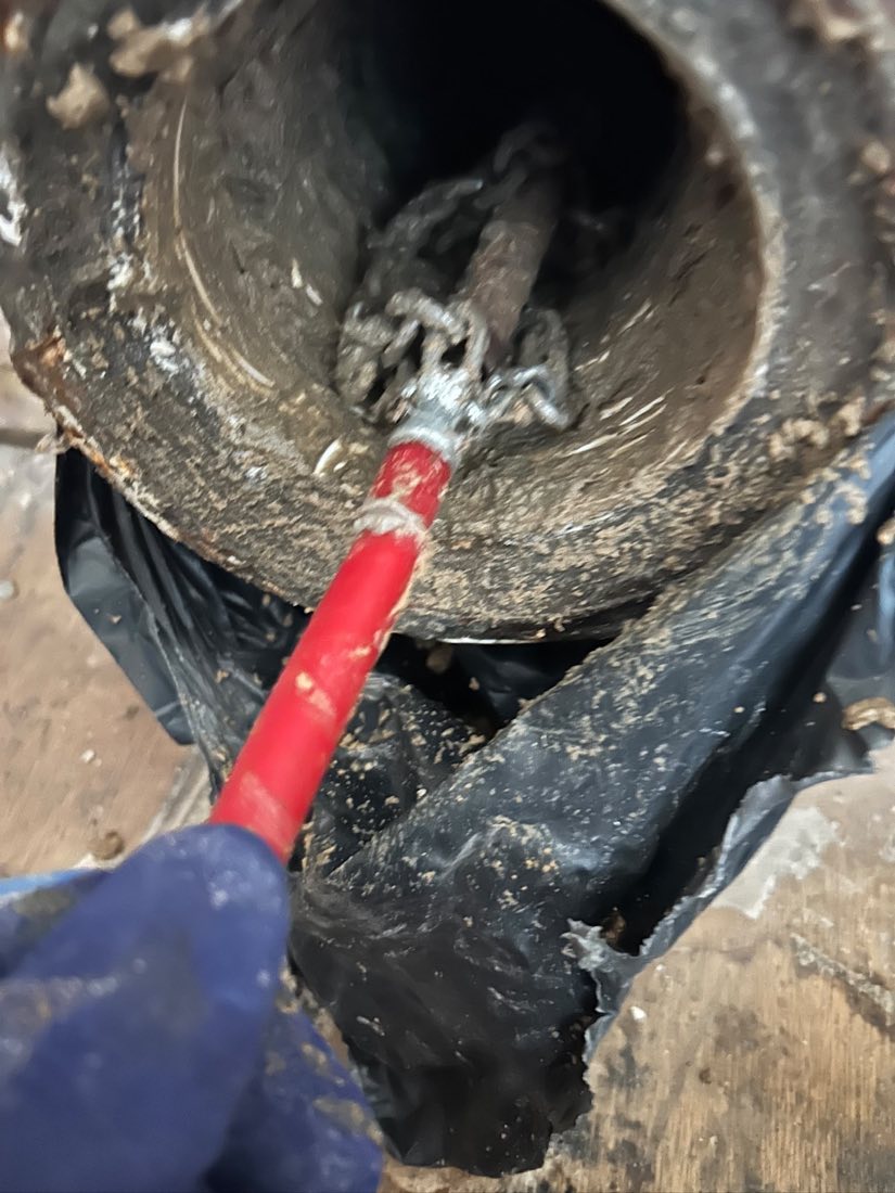 A flex shaft chain head inside a scaled cast iron pipe, part way through descaling.