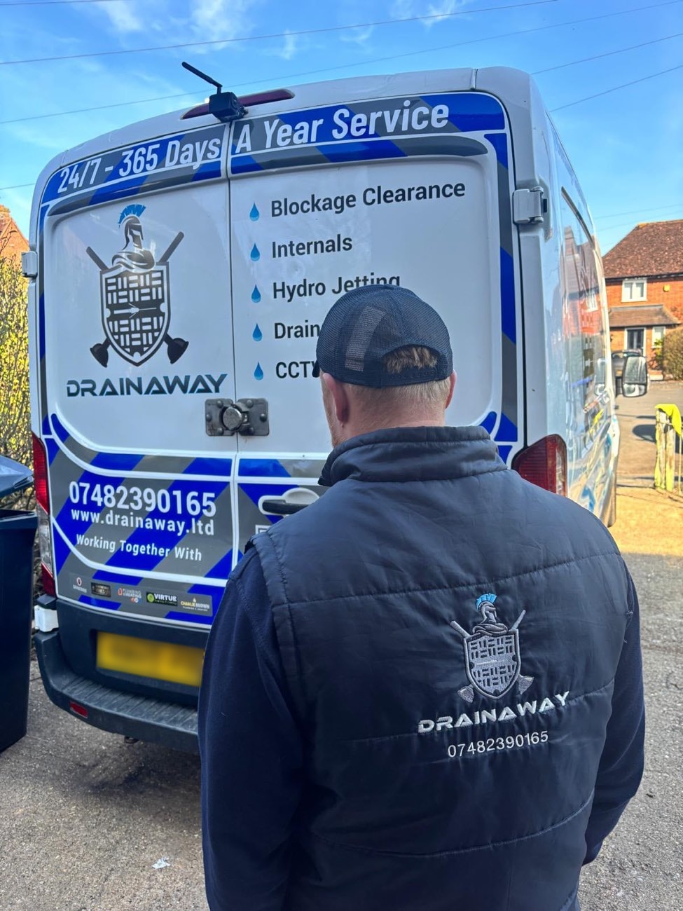 A DrainAway engineer at the rear of a liveried van listing blockage clearance, hydro jetting and CCTV services.