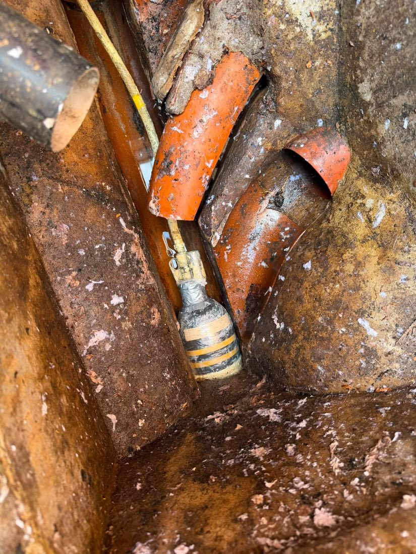 A patch liner being installed into a defective section of clay drain pipework in an open excavation.
