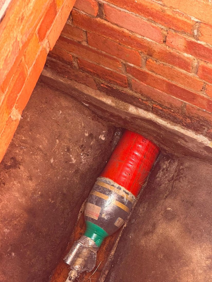 A patch liner wrapped around an inflatable packer, fed into the pipe at the base of a brick chamber ready to cure.