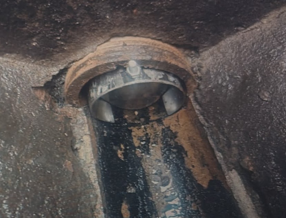 A rodent blocker fitted into the pipe opening in a chamber wall, its flaps closed against the bore.