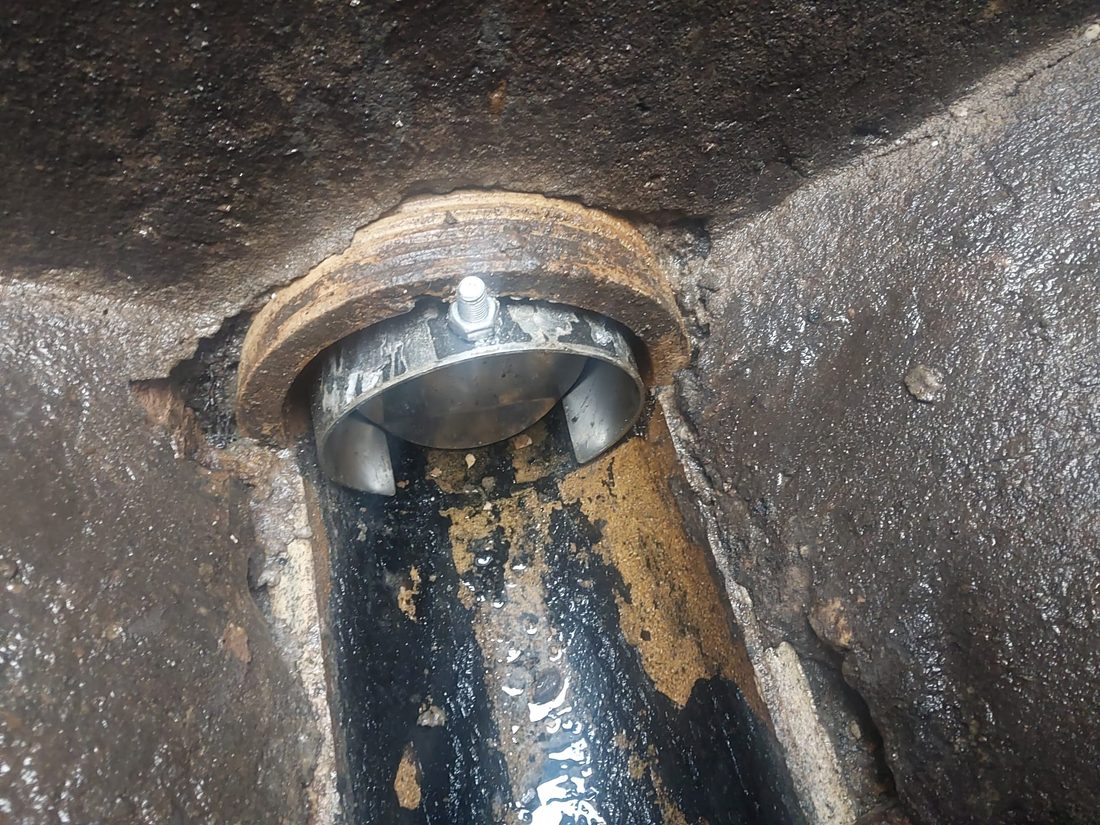 A rodent guard bolted into the end of a drain pipe where it enters an inspection chamber, blocking rat access.